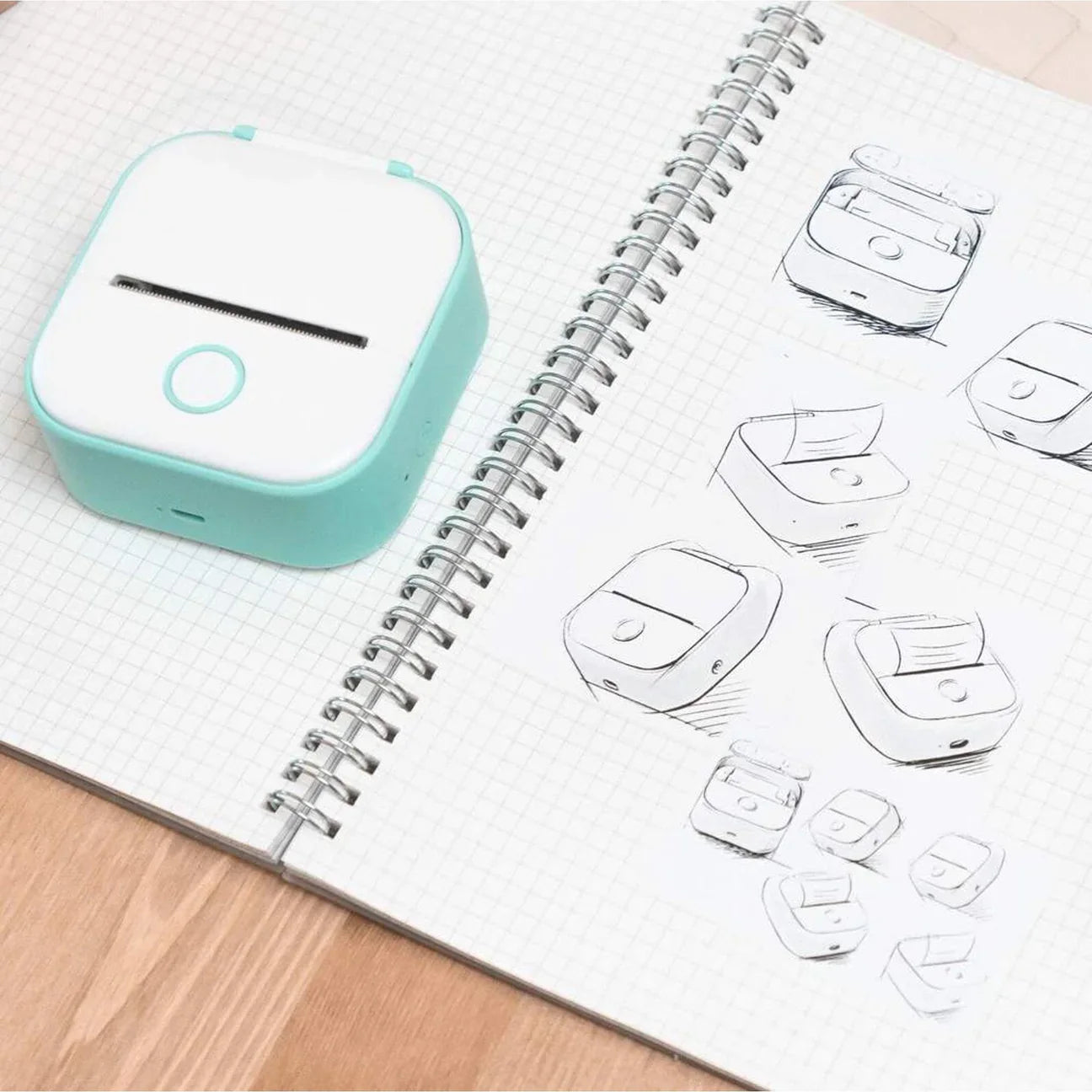 Turquoise device on an open notebook with sketches of similar devices.